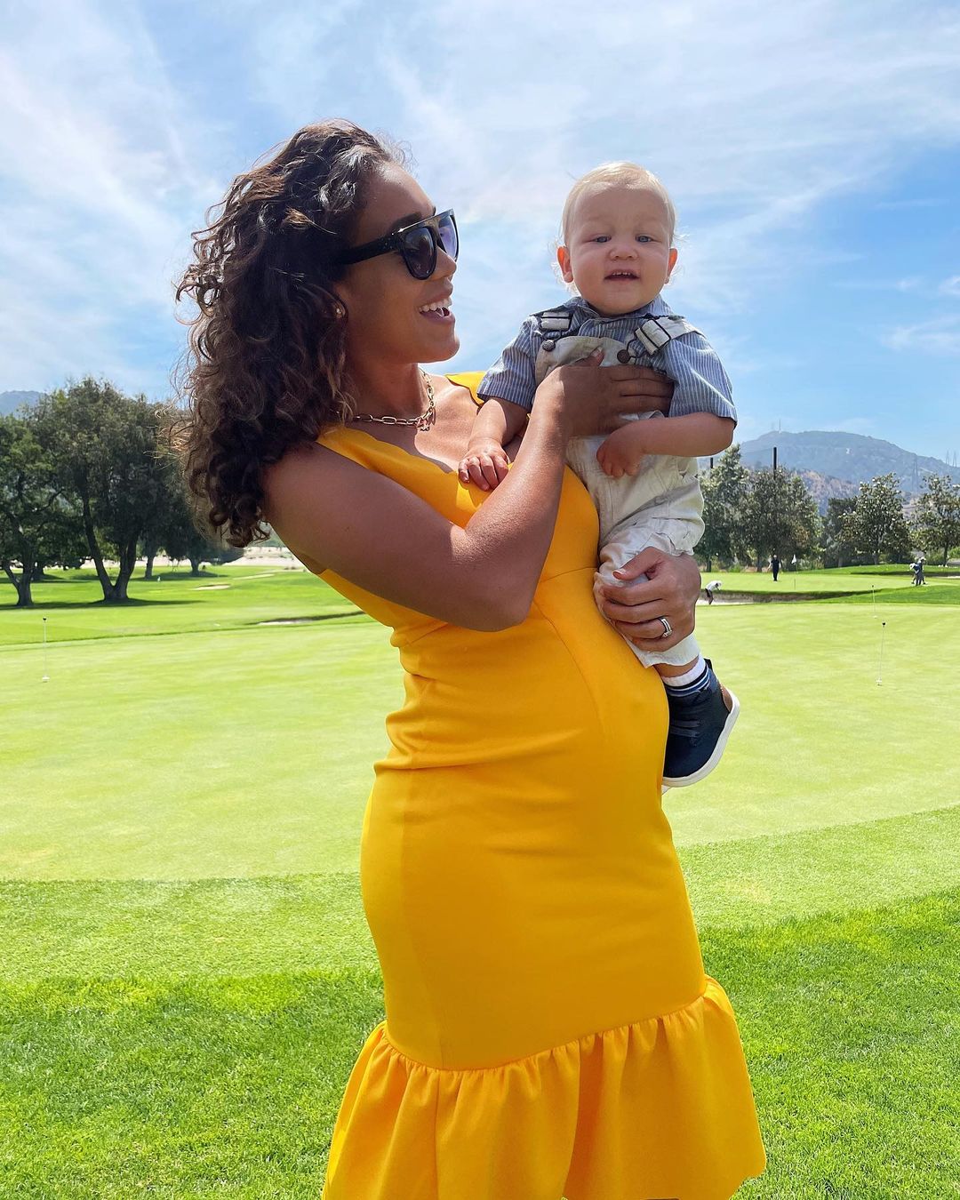 Simone Boyce holding her son in a yellow dress